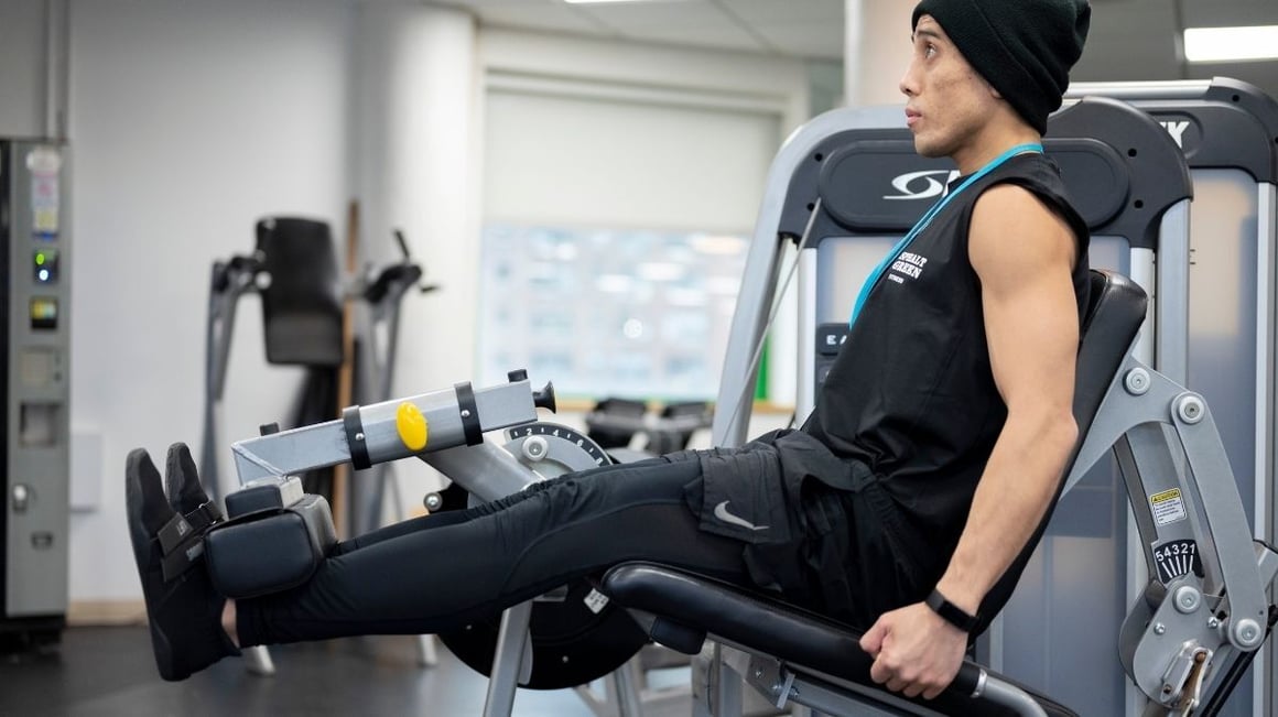 Asphalt Green trainer demonstrating the leg extension machine at our fitness center